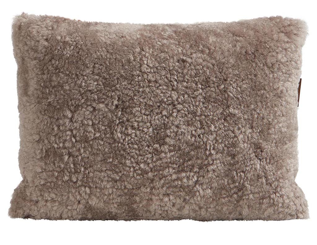 En kudde med framsida i korthårig mjuk fårskinn med sitt ursprung ifrån Australien och baksida i vävd ull med måtten 40x30cm
