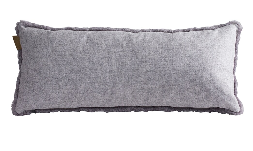 En kudde med framsida i korthårig mjuk fårskinn med sitt ursprung ifrån Australien och baksida i vävd ull med måtten 60x25cm