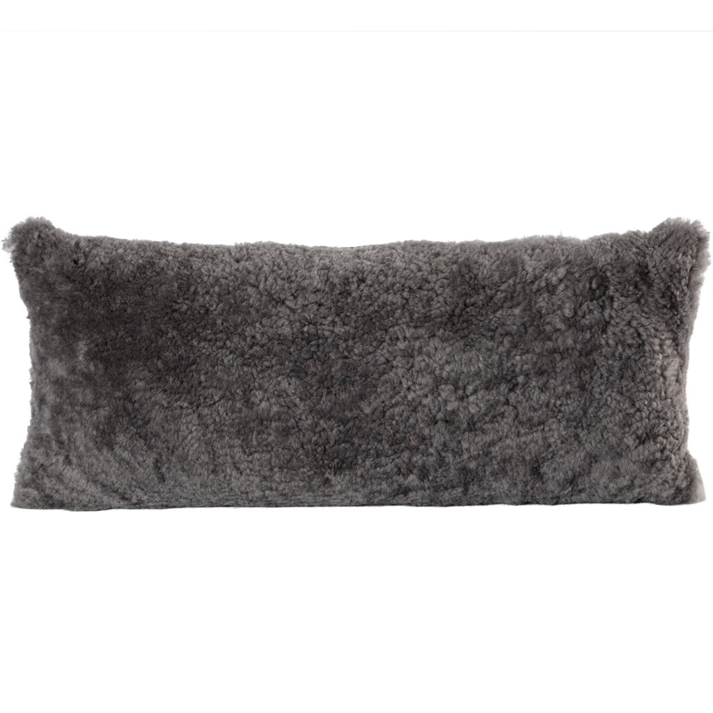 En kudde med framsida i korthårig mjuk fårskinn med sitt ursprung ifrån Australien och baksida i vävd ull med måtten 60x25cm